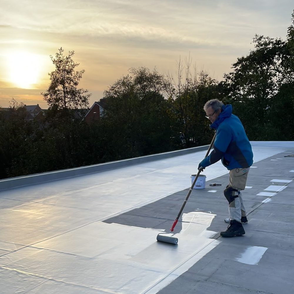 Vakman Verhelle aan het werk als dakwerker: bescherming aanbrengen op plat dak